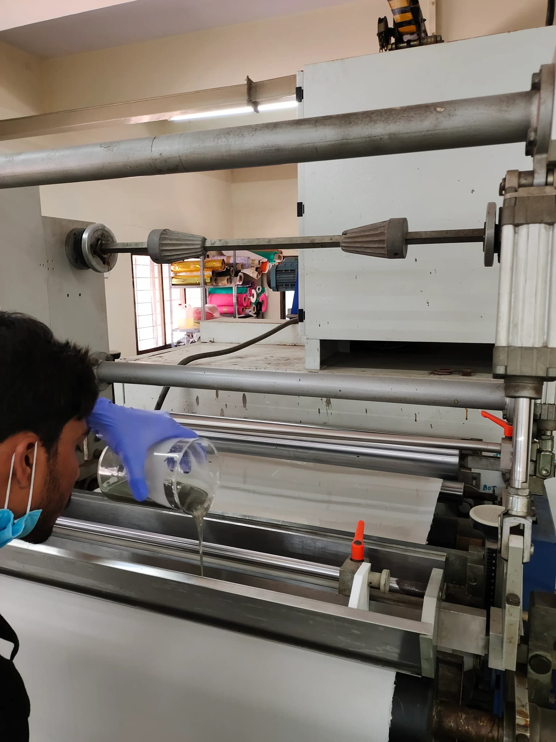 Technician pouring coating formulation onto the roller of a coating and lamination line