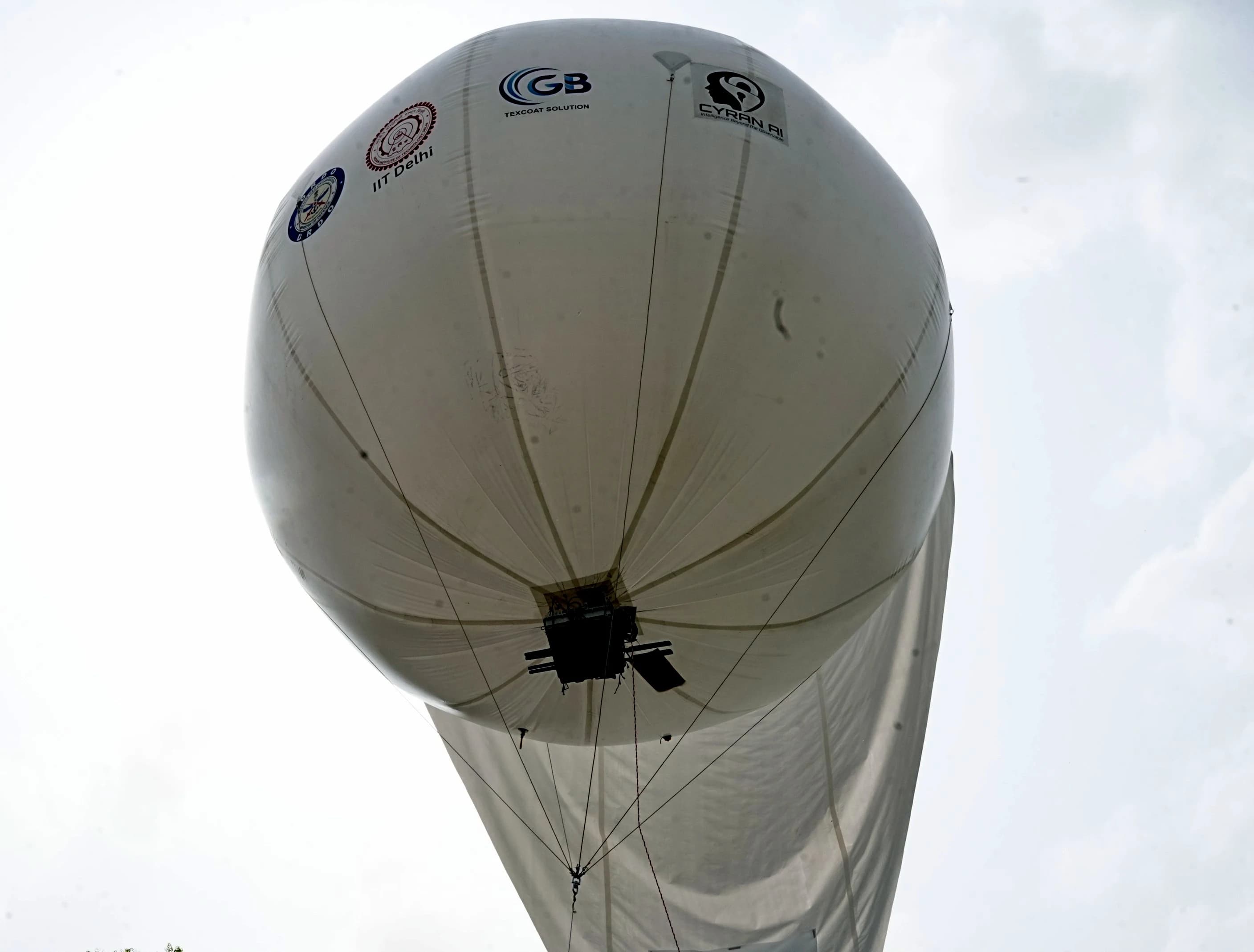 Close view of the aerostat envelope in flight, showing partner branding